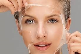 Na zdjęciu widoczna jest kobieta, która delikatnie zdejmuje przezroczystą maskę z twarzy. Proces ten jest najprawdopodobniej częścią zabiegu kosmetycznego, takiego jak peeling chemiczny. Skóra kobiety wygląda na świeżą i promienną, co sugeruje, że zabieg miał na celu złuszczenie martwego naskórka, poprawę tekstury skóry oraz nadanie jej zdrowego blasku.