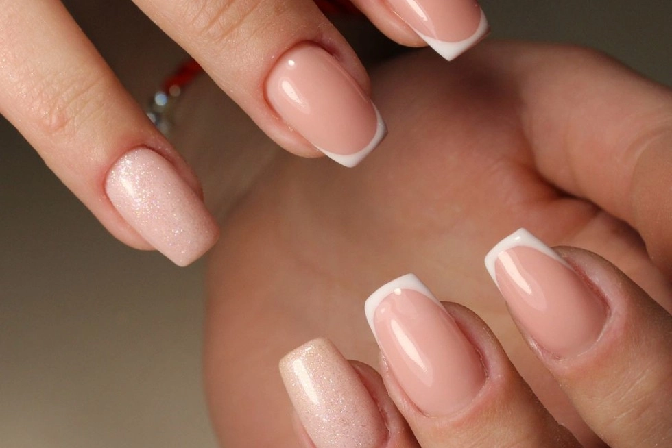 Dłonie ze świątecznym manicurem w perłowych odcieniach