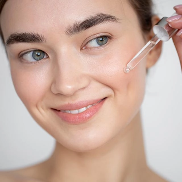 Kobieta nakładająca serum z retinolem na skórę twarzy